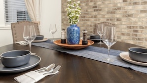 A dining table set with blue bowls, wine glasses, and a blue vase with white flowers. - Cozy, Downtown Boise, BSU, Getaway! (Boise)