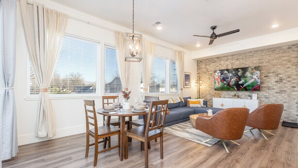 A modern living room with a dining area, featuring a brick wall, a large flat-screen TV, and a ceiling fan. - Downtown Boise, BSU, Adventures! (Boise)