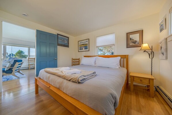 A bedroom with a bed, a nightstand, a window, and a door leading to a balcony.