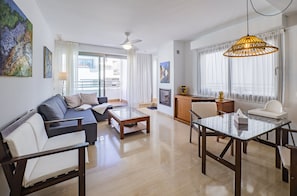 Relax in a spacious living area with a sofa, chairs, and dining table, surrounded by artwork and natural light.