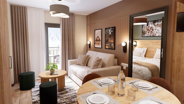 A modern hotel room with a sofa, dining table set for two, and a bed with a wooden headboard.