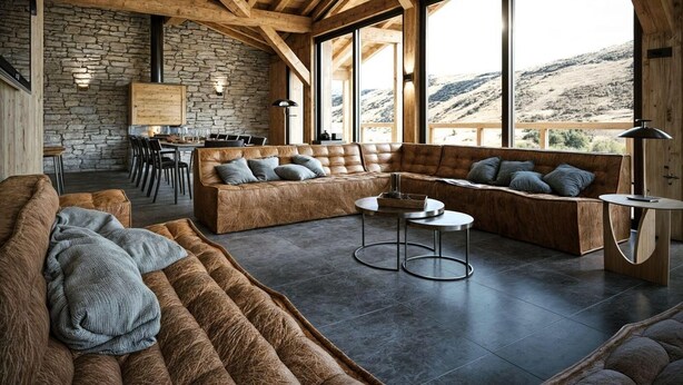 A spacious living area with a stone wall, large windows, and a view of the mountains.