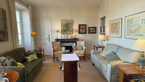 Cozy living room with a green sofa, light blue sofa, and wooden coffee table, featuring a fireplace and bookshelf.