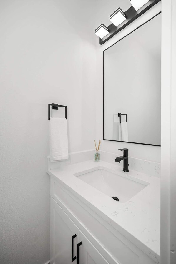 A modern bathroom with a white vanity, two sinks, a large mirror, and a towel rack. - Modern Villa with Scenic Views (Spokane)