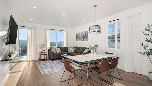 A spacious living area with a dining table, sofas, and a TV.
