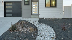 A modern two-story house with a garage, a front door with glass panels, and a driveway leading to the entrance.