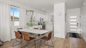 A modern kitchen with white cabinets, a stainless steel refrigerator, and a built-in oven.