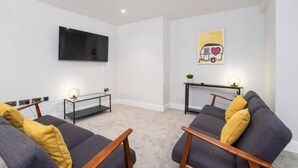 A living room with two sofas, a flat-screen TV, a small table, and a wall-mounted artwork. - The Old Hotel - Nether Hornpot (Clifton)