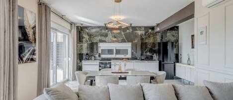 Un salón moderno con sofá, mesa de comedor y cocina al fondo.