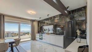A modern kitchen with a large island, a built-in oven, and a refrigerator. - Villa La Vie (Podstrana)
