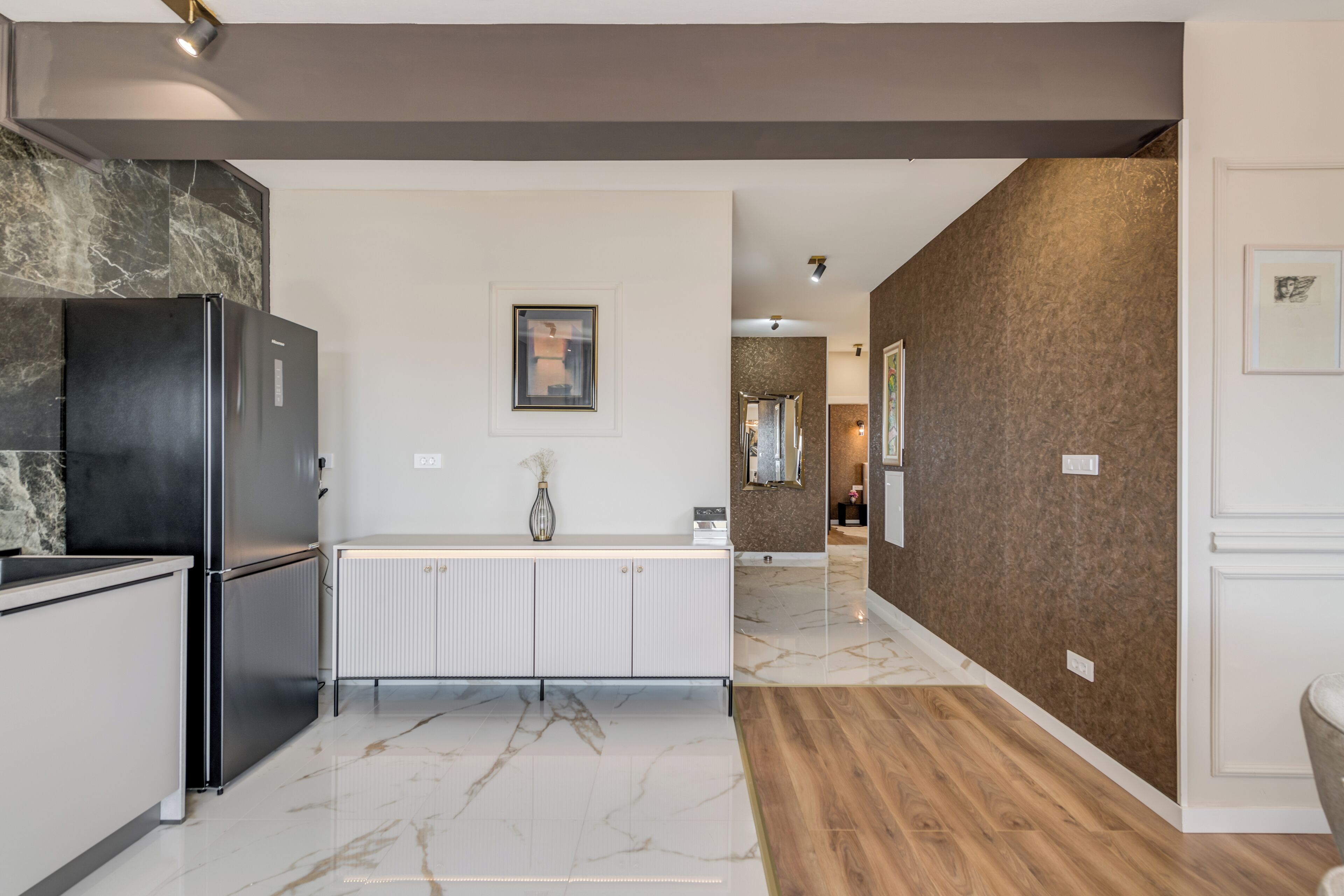 A modern kitchen with a black refrigerator, white cabinetry, and a marble floor.