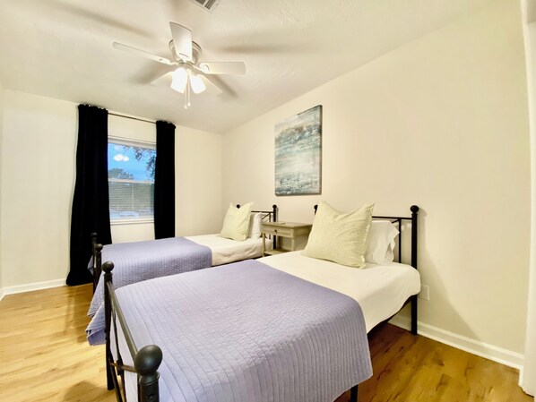 A hotel room with two beds, a ceiling fan, a window with curtains, and a painting on the wall. - Conveniently Located Masters Rental- Walking Distance to Hammonds Ferry! (North Augusta)