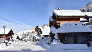A snow-covered village with wooden buildings, a clear sky, and a snow-covered road. - 250m from shops, 2nd floor, balcony, tv, ski locker, 75m², Méribel (Méribel - Les Allues)