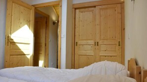 A bedroom with a large bed, wooden wardrobe, and a door leading to another room. - 250m from shops, 2nd floor, balcony, tv, ski locker, 75m², Méribel (Méribel - Les Allues)