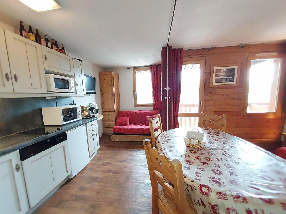 A compact kitchen with white cabinets, a microwave, and a dining area with a table and chairs.