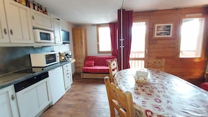 A compact kitchen with white cabinets, a microwave, and a dining area with a table and chairs.