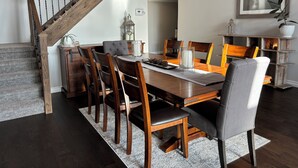 A dining area with a wooden table, chairs, and a staircase. - Cozy Home on Sturgeon Lake with Hot Tub (Kawartha Lakes)