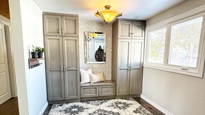 A hallway with a patterned rug, wooden flooring, and a bench with cushions. - Cozy Home on Sturgeon Lake with Hot Tub (Kawartha Lakes)