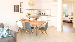 A modern kitchen with white cabinets, a wooden island, and a dining area with a wooden table and chairs.