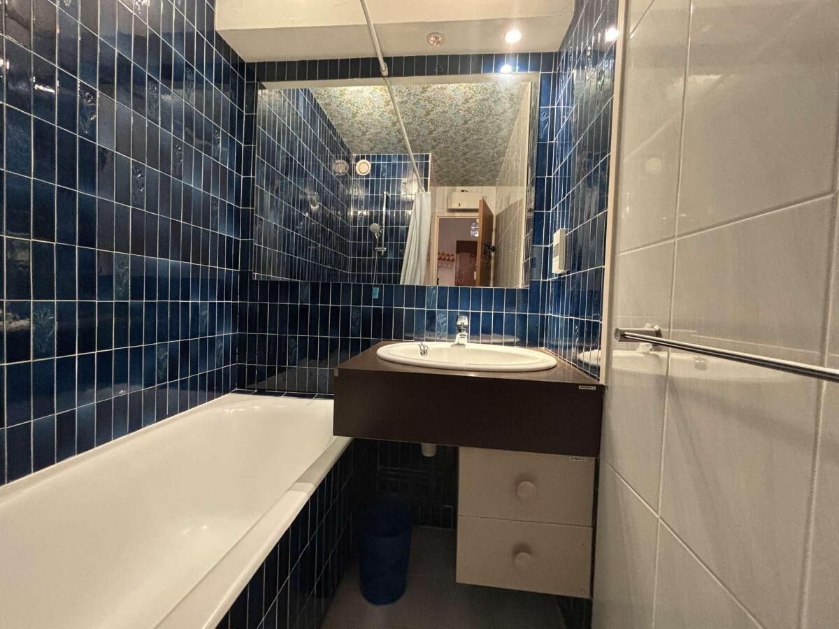 A bathroom with a bathtub, a sink, and a mirror.