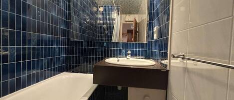 A bathroom with a bathtub, a sink, and a mirror.