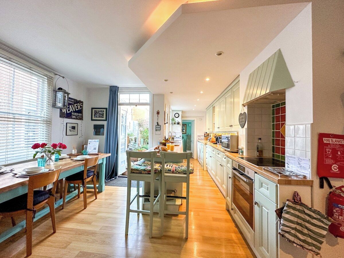 Una cucina moderna con pavimento in legno, zona pranzo con tavolo e sedie, e un cartello di sicurezza antincendio ben visibile.