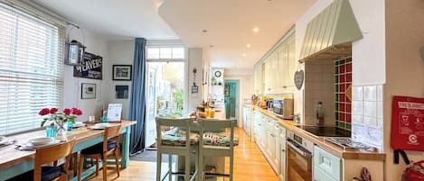 Une cuisine moderne avec un plancher en bois, un coin repas comprenant une table et des chaises, et un panneau de sécurité incendie bien visible.