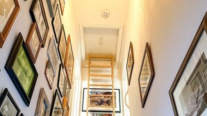 A staircase with a wooden handrail, carpeted steps, and a wall adorned with framed pictures.