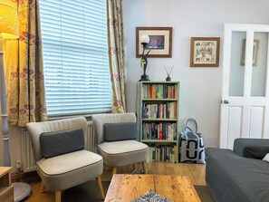 Un salon avec un canapé, des fauteuils, une bibliothèque et une porte.