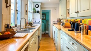 A kitchen with wooden countertops, white cabinets, a sink, and a window.