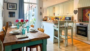 A cozy kitchen with wooden cabinets, a dining table set for four, and a view of the street outside.