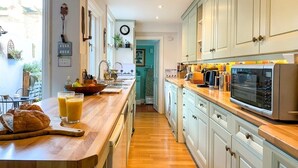 A modern kitchen with wooden countertops, white cabinets, and a microwave.