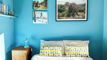 A bedroom with a bed, pillows, a nightstand, and wall art.