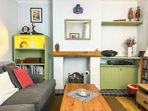 Een gezellige woonkamer met een bank, een bijzettafeltje, een boekenkast en een open haard.