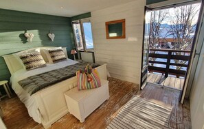A bedroom with a bed, bedside table, and a view of a snowy landscape through a sliding door.
