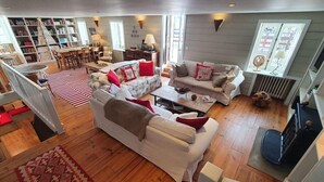 A cozy living room with a fireplace, a bookshelf, and a dining area. - Chalet, wifi, 130m from resort center, sauna, terrace, parking, tv, ski locker, 450m², Alpe d'Huez (L'Alpe d'Huez)