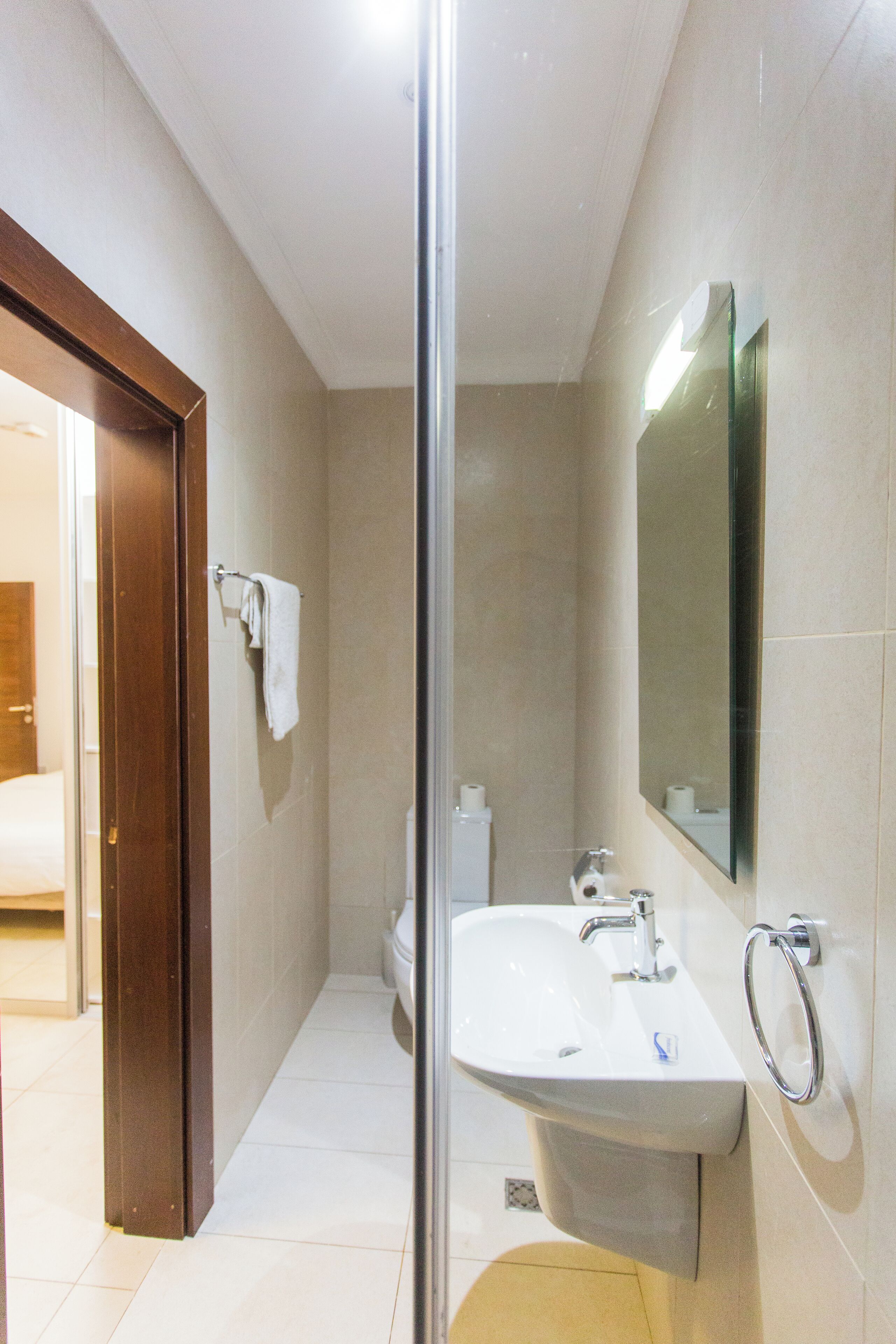 Un bagno moderno con box doccia in vetro, lavandino bianco e un ampio specchio.