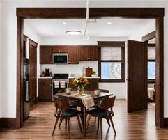 Una cocina moderna con armarios de madera oscura, un refrigerador de acero inoxidable y un comedor con mesa y sillas.