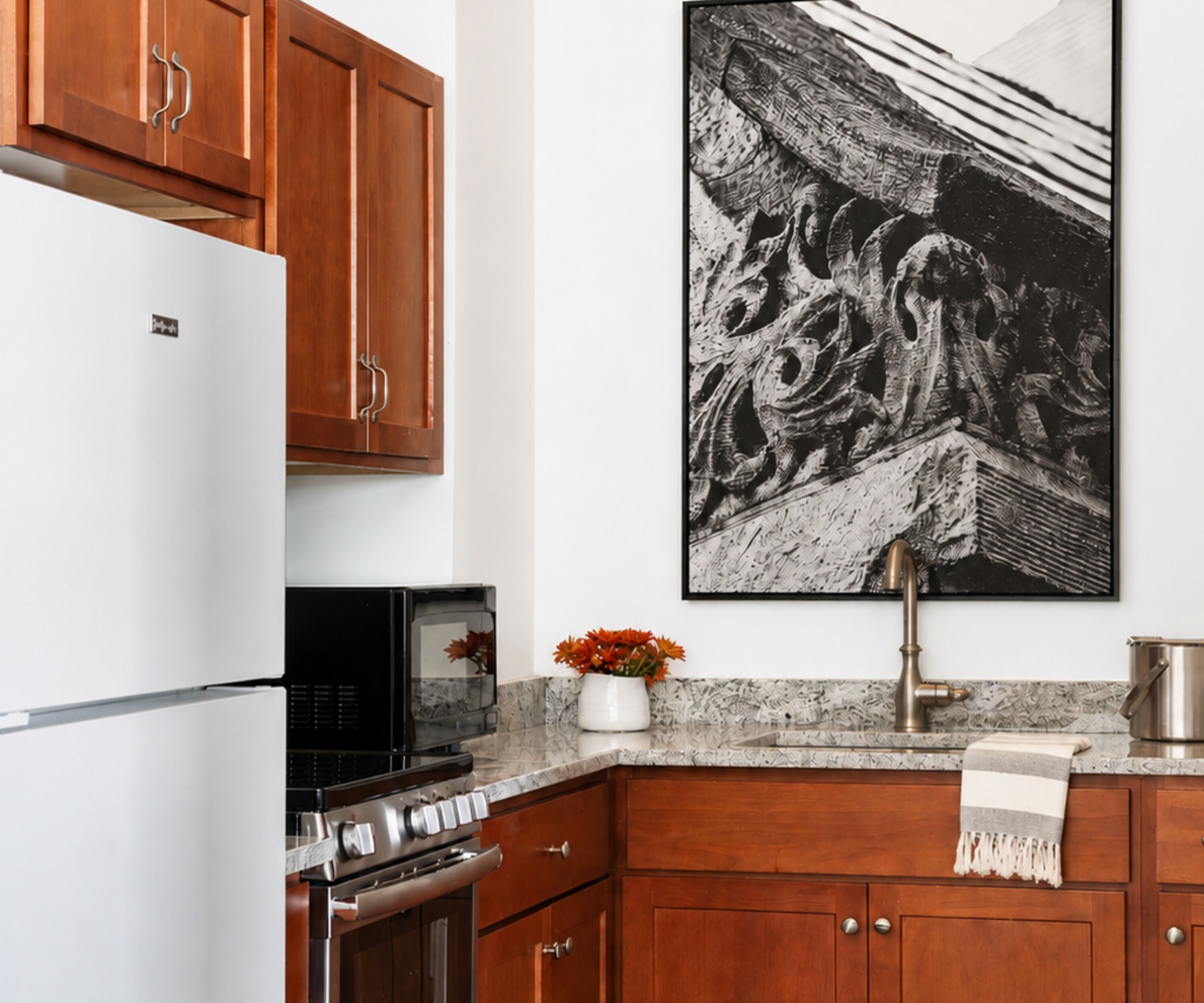 A kitchen with wooden cabinets, a refrigerator, a microwave, a stove, and a sink.