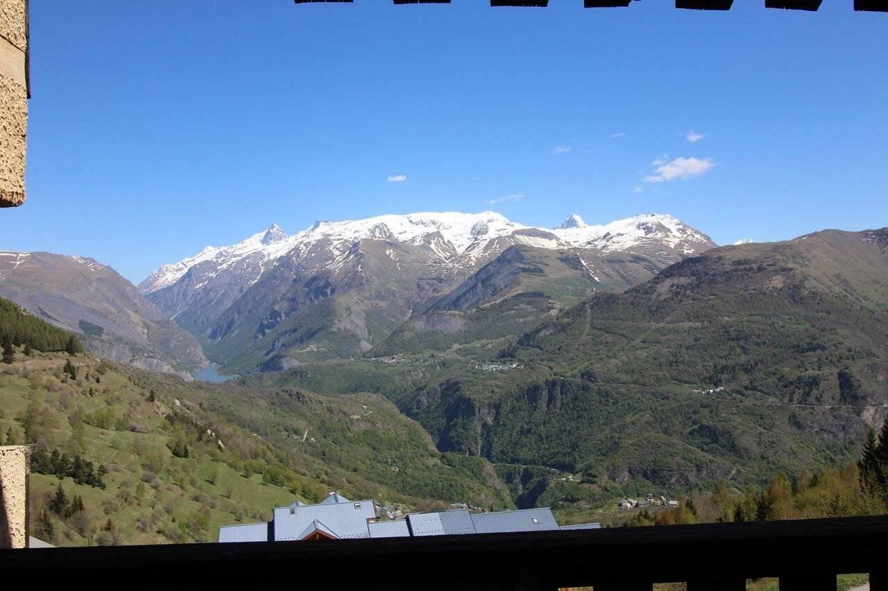 A mountainous landscape with snow-capped peaks and a valley with greenery.