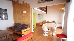 Un'accogliente stanza con un divano in legno, un tavolo da pranzo con sedie e un armadietto in legno.