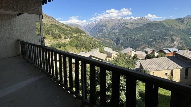 Ein Balkon mit Blick auf eine Berglandschaft und ein Dorf darunter.