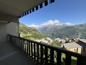 A balcony with a view of a mountainous landscape and a village below. - Ski-in/ski-out & foot of the slopes, Ground floor, tv, ski locker, 45m², Auris en Oisans (Auris)
