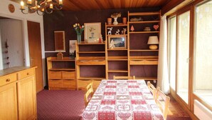 Ein gemütlicher Essbereich mit einem Holztisch, gedeckt für vier Personen, umgeben von Holzböden und einem Kronleuchter.