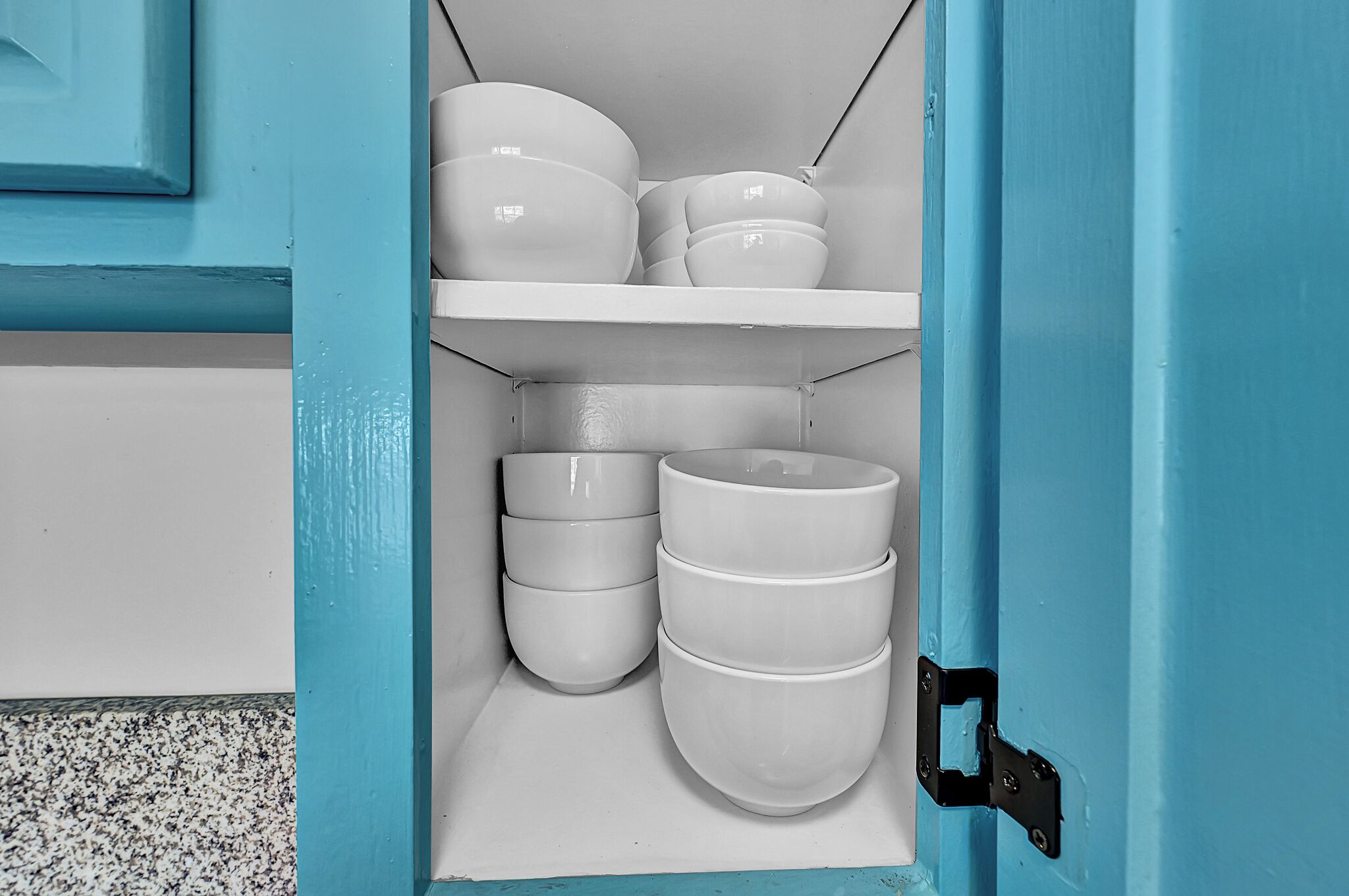 Una cocina con armarios blancos y una puerta azul.