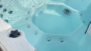 Een jacuzzi met helder water, bubbels en een draineerput in de vorm van een ster.