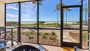Ein Zimmer mit großen Fenstern und Blick auf Strand und Palmen.