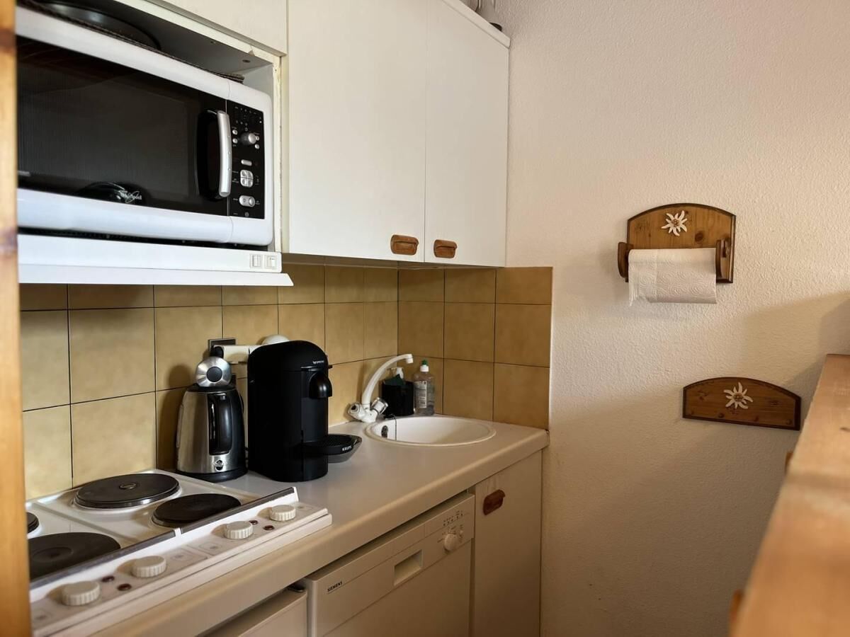 Une petite cuisine équipée avec une cuisinière, une machine à café, un four à micro-ondes et un évier.