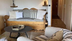A cozy room with a wooden bed, a round table, and a sofa. - 5m from ski slopes, floor -2, view mountain, balcony, 34m², Méribel-Mottaret (Méribel - Les Allues)