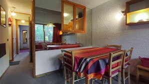 Une cuisine compacte comprenant une table à manger, des chaises et un meuble avec des portes miroir.
